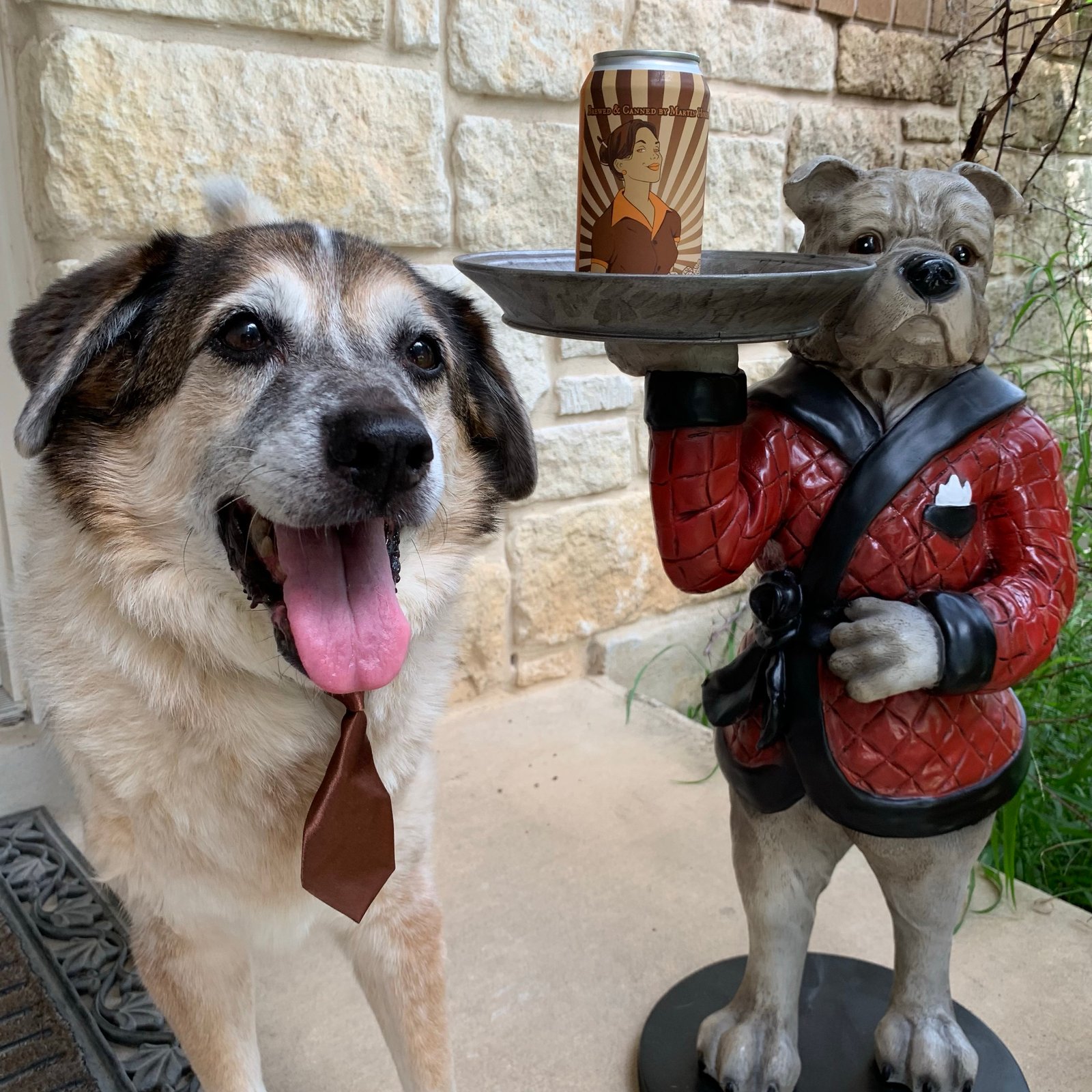 dog in brown tie next to beer and dog butler statue