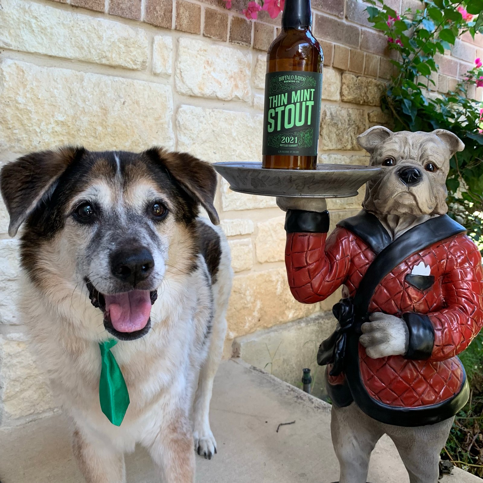 dog in green tie next to beer and dog butler statue